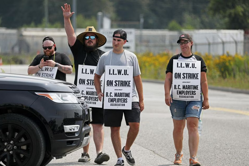 Dockworkers wearing picket signs at the front gate of the dock.